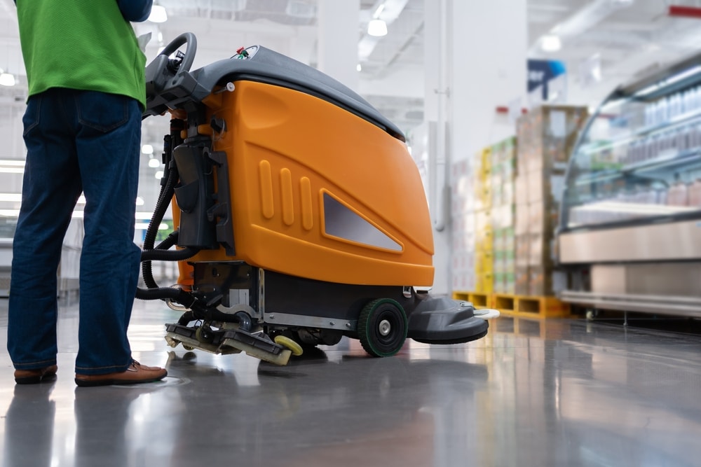 Nettoyage d'escalier en granit avec serpillière microfibre Mise au point sur une serpillière microfibre bleue et blanche nettoyant une marche d'escalier en granit moucheté, un seau bleu est visible en arrière-plan.